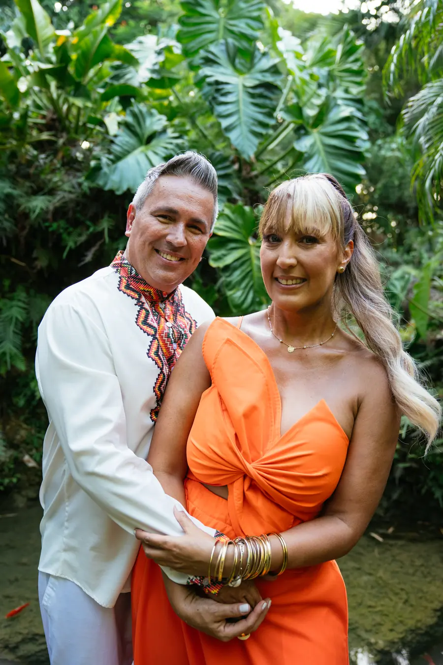 Tania and Abraham embracing in a tropical garden, smiling