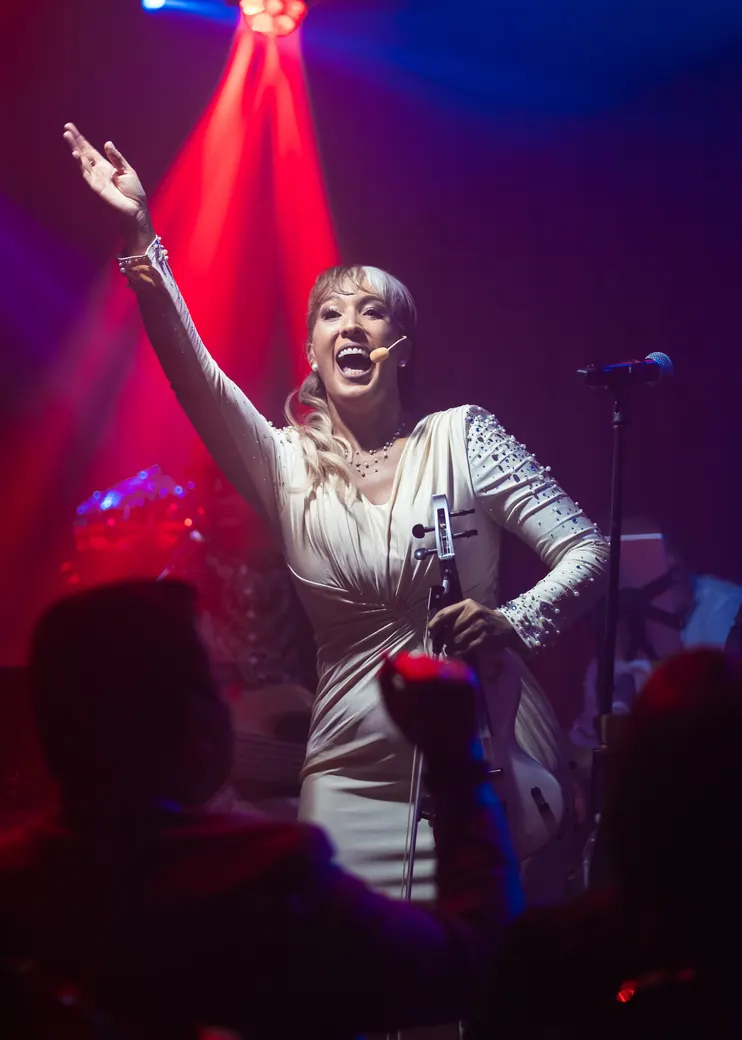 On stage, arm raised, under red and blue lights
