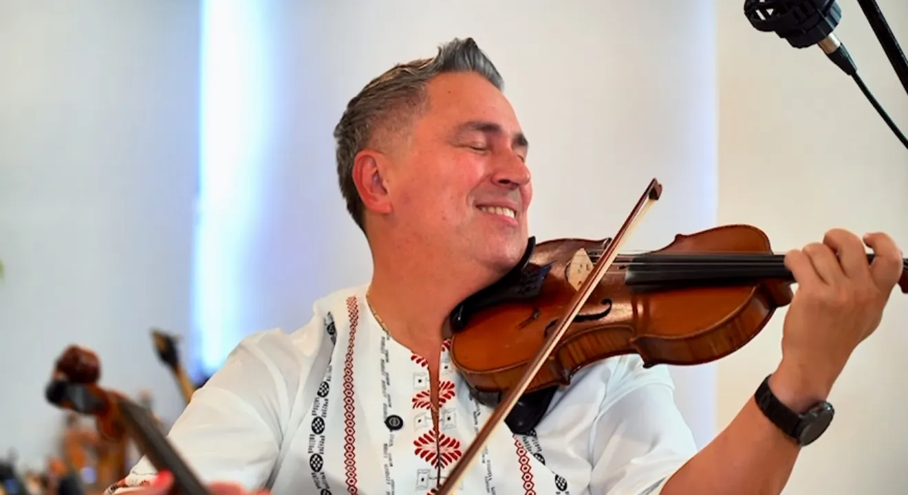Playing violin with eyes closed, smiling